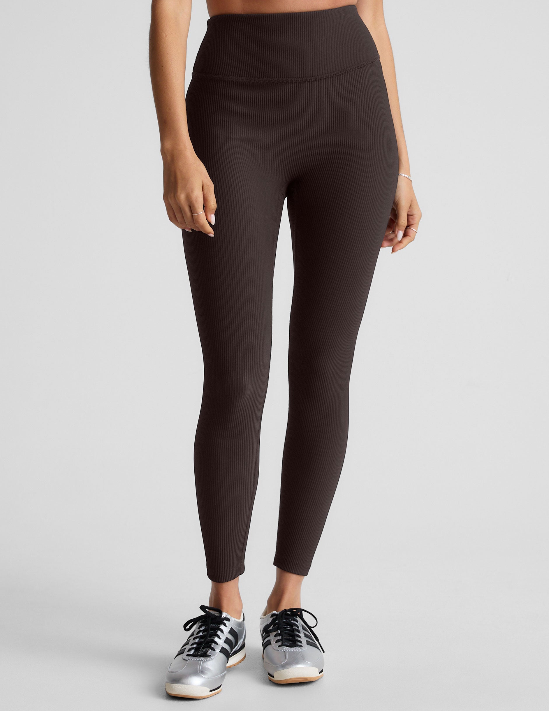 model wearing brown ribbed high-waisted midi length leggings against a plain background.