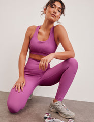 pink medium support racerback bra with a scoop neckline​, overlapping hemband detail​, is lined with performance lining and powermesh in between​, and has removable bra pads​. 