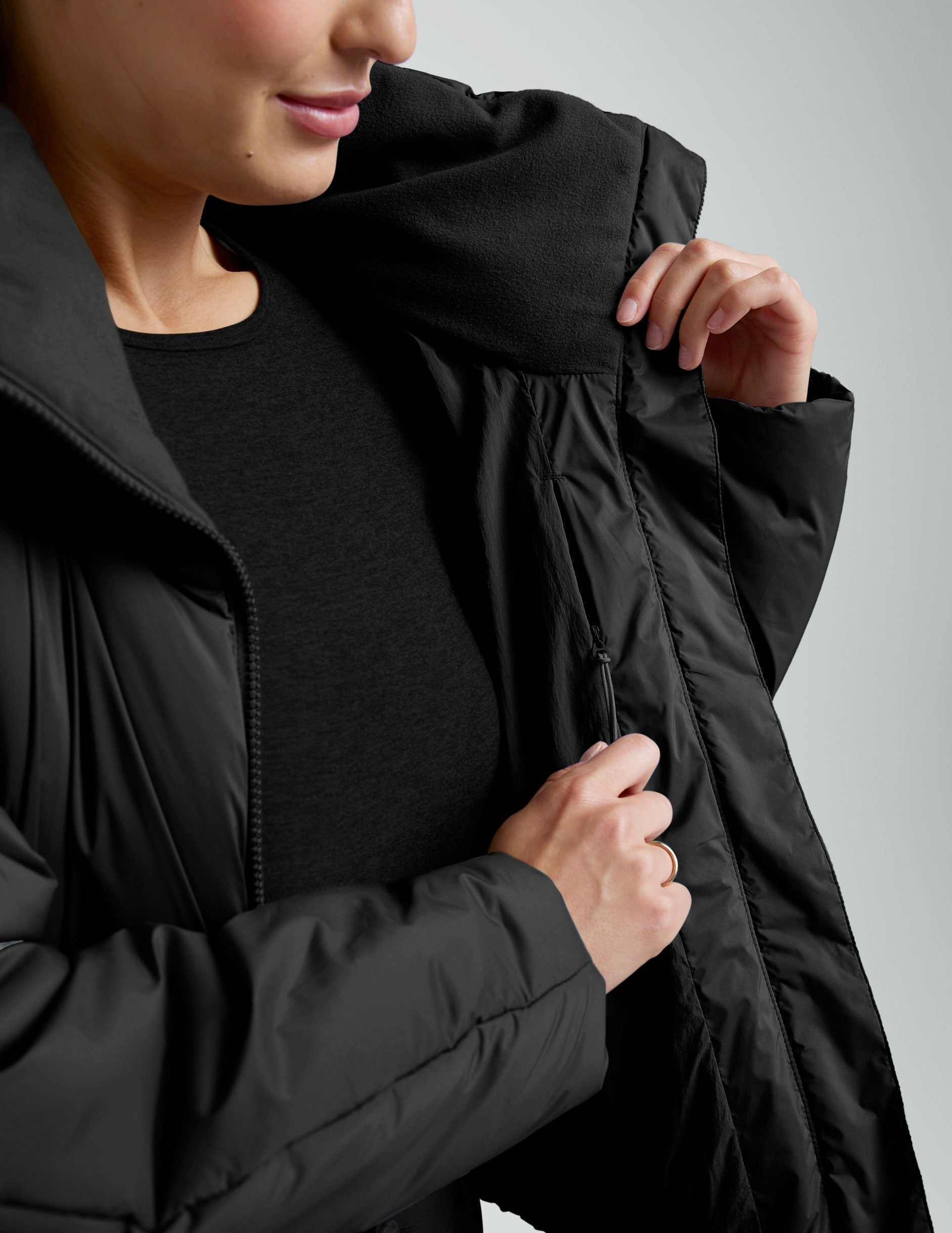 Person wearing a black zip-up puffer jacket and pants on a plain background.