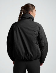 Person wearing a black zip-up puffer jacket and pants on a plain background.