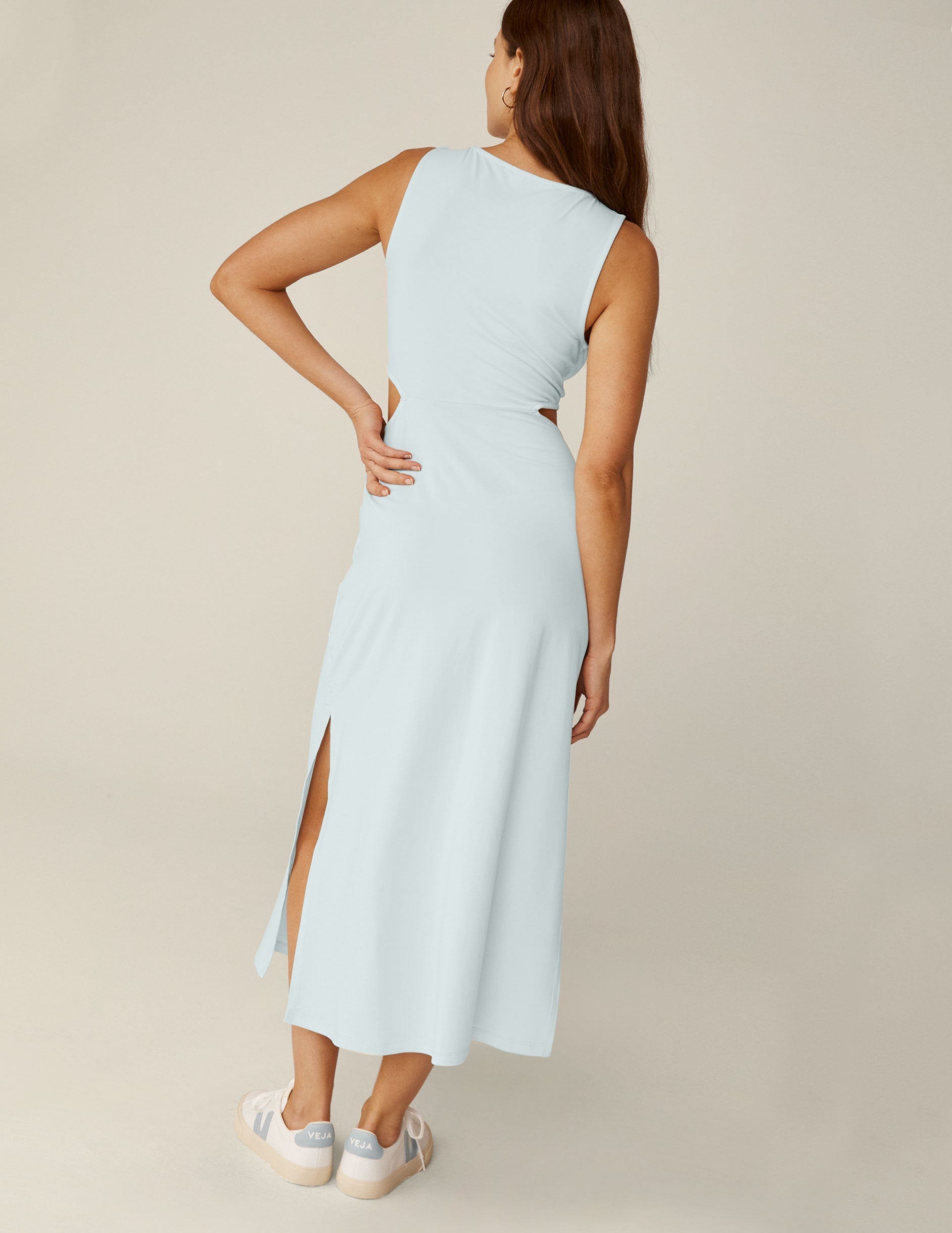 model is wearing a blue tank top maxi dress with a twist detailing and side cutouts.