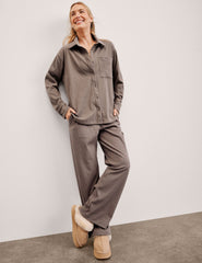 woman wearing a brown corduroy button down shirt and pants against a plain background.