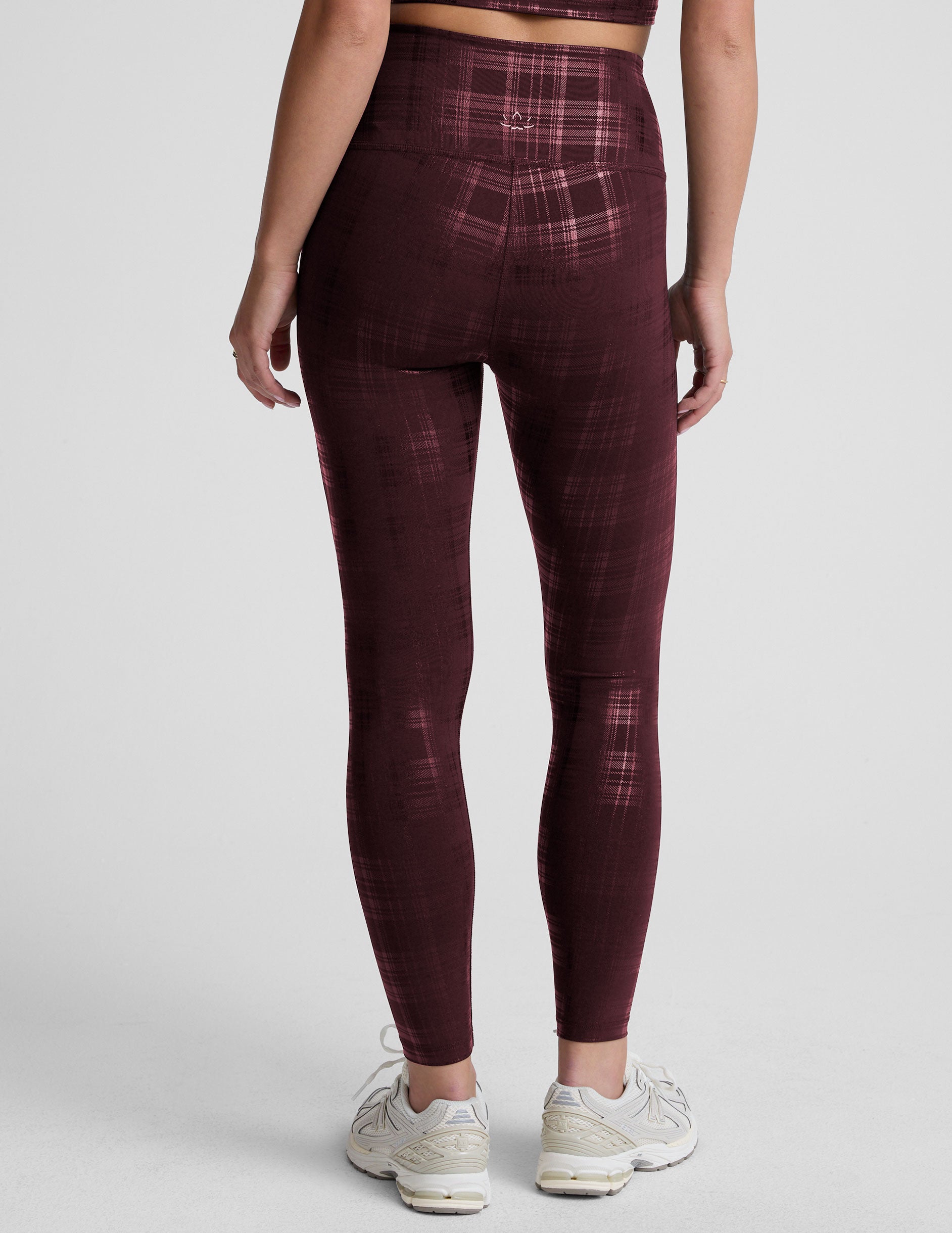 model wearing a plaid foil high-waisted midi leggings on a light gray background.