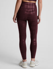 model wearing a plaid foil high-waisted midi leggings on a light gray background.