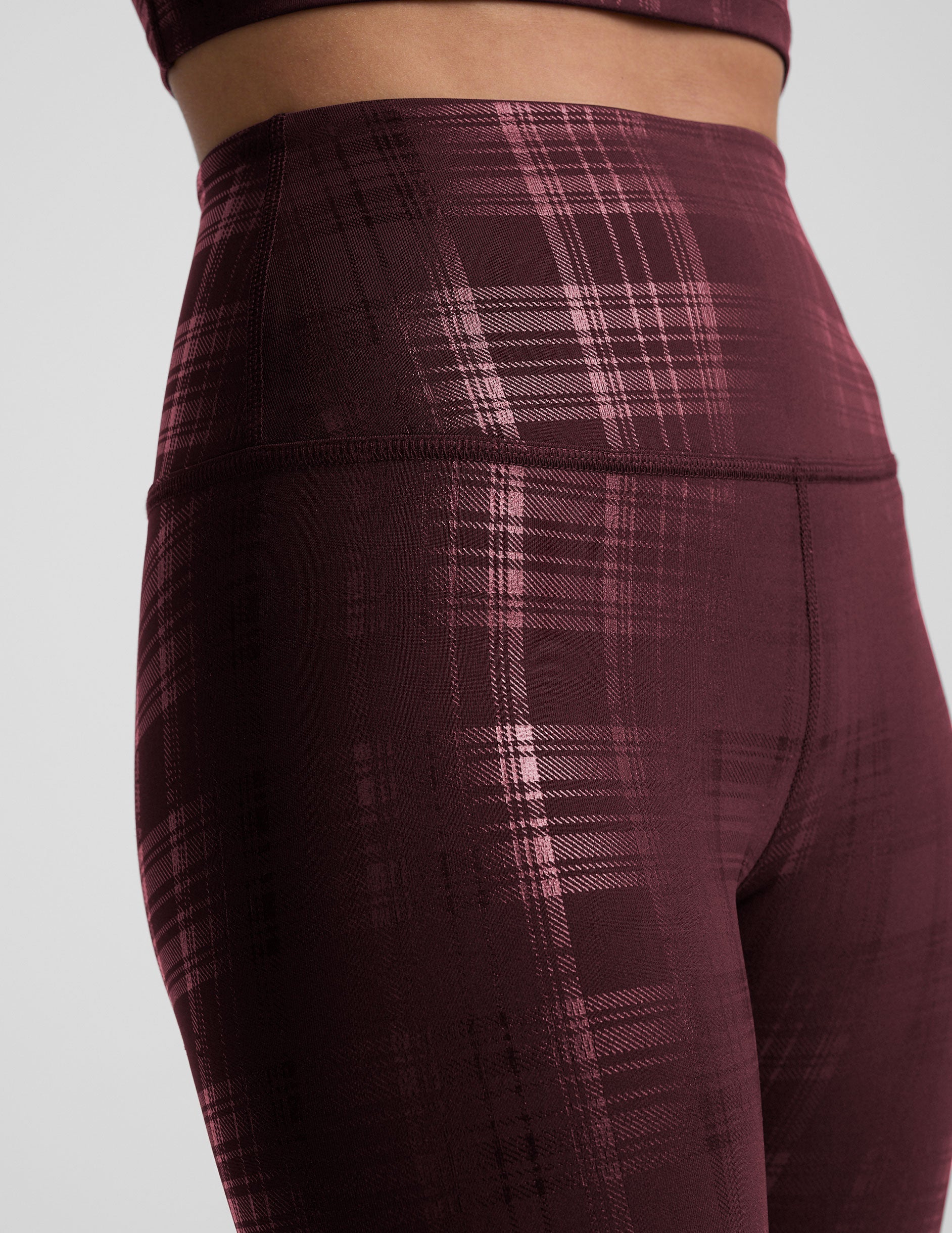 model wearing a plaid foil high-waisted midi leggings on a light gray background.