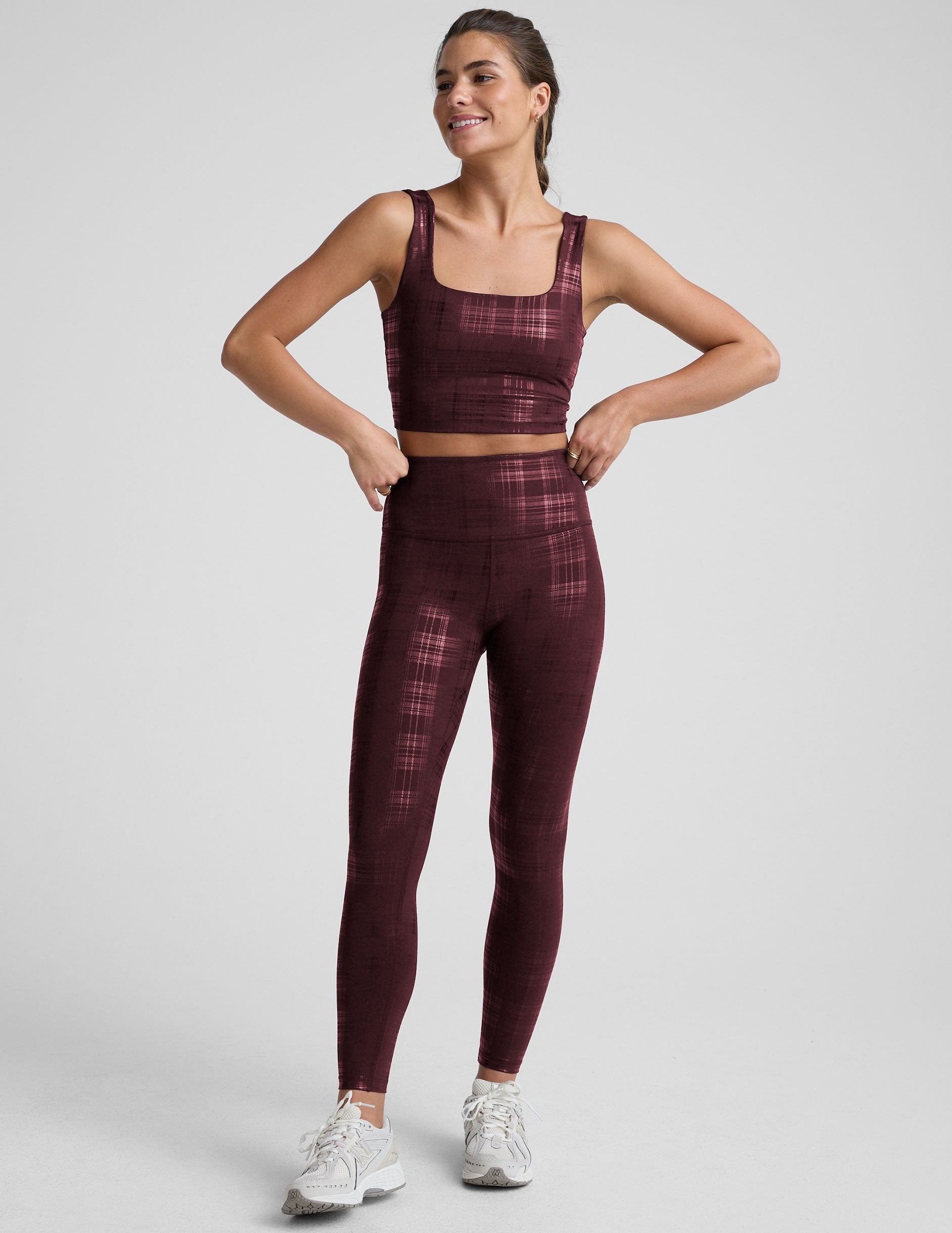 model wearing a plaid foil cropped tank  and high-waisted midi leggings set on a light gray background.