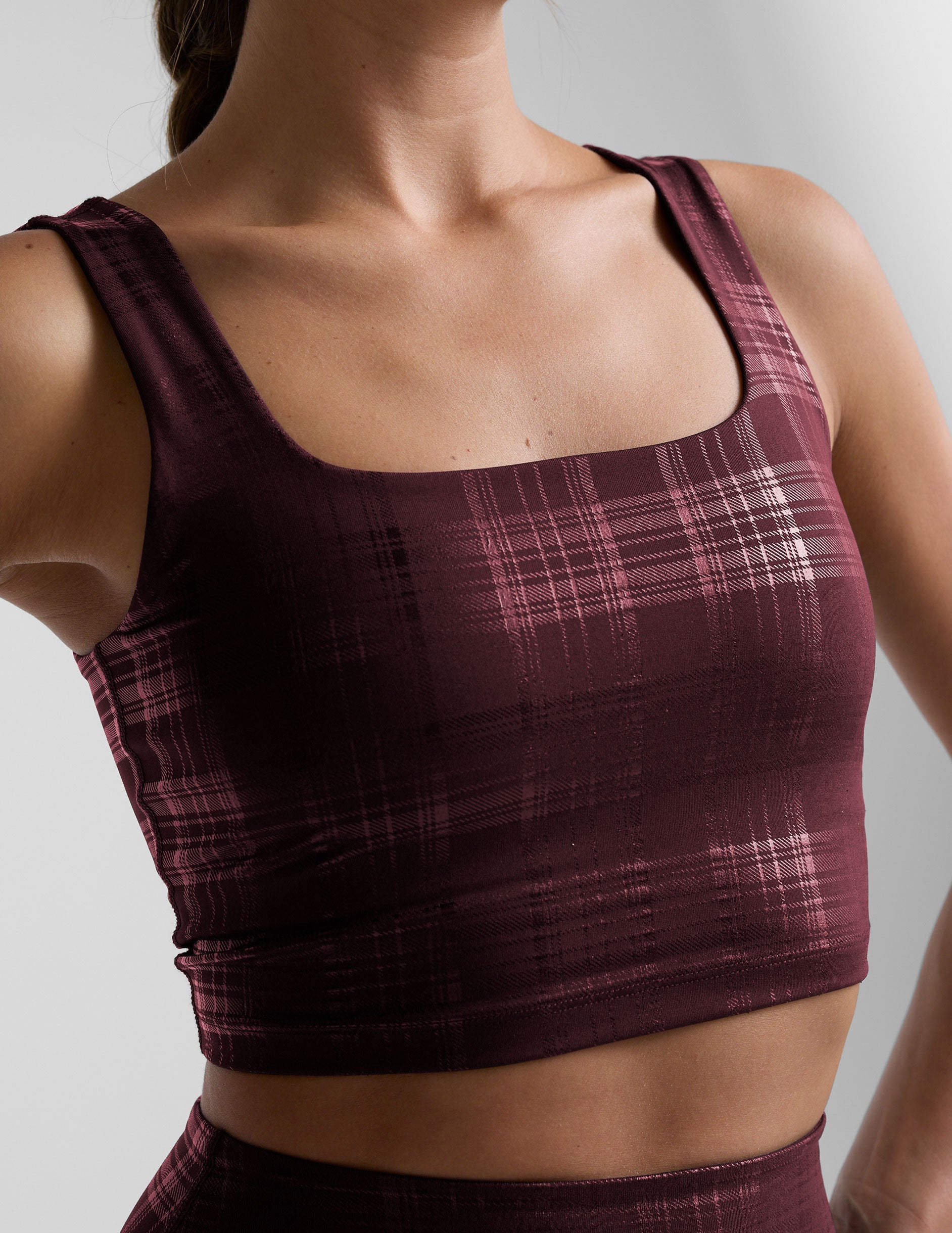 model wearing a red plaid foil printed square neck cropped tank top and matching leggings against a plain background.