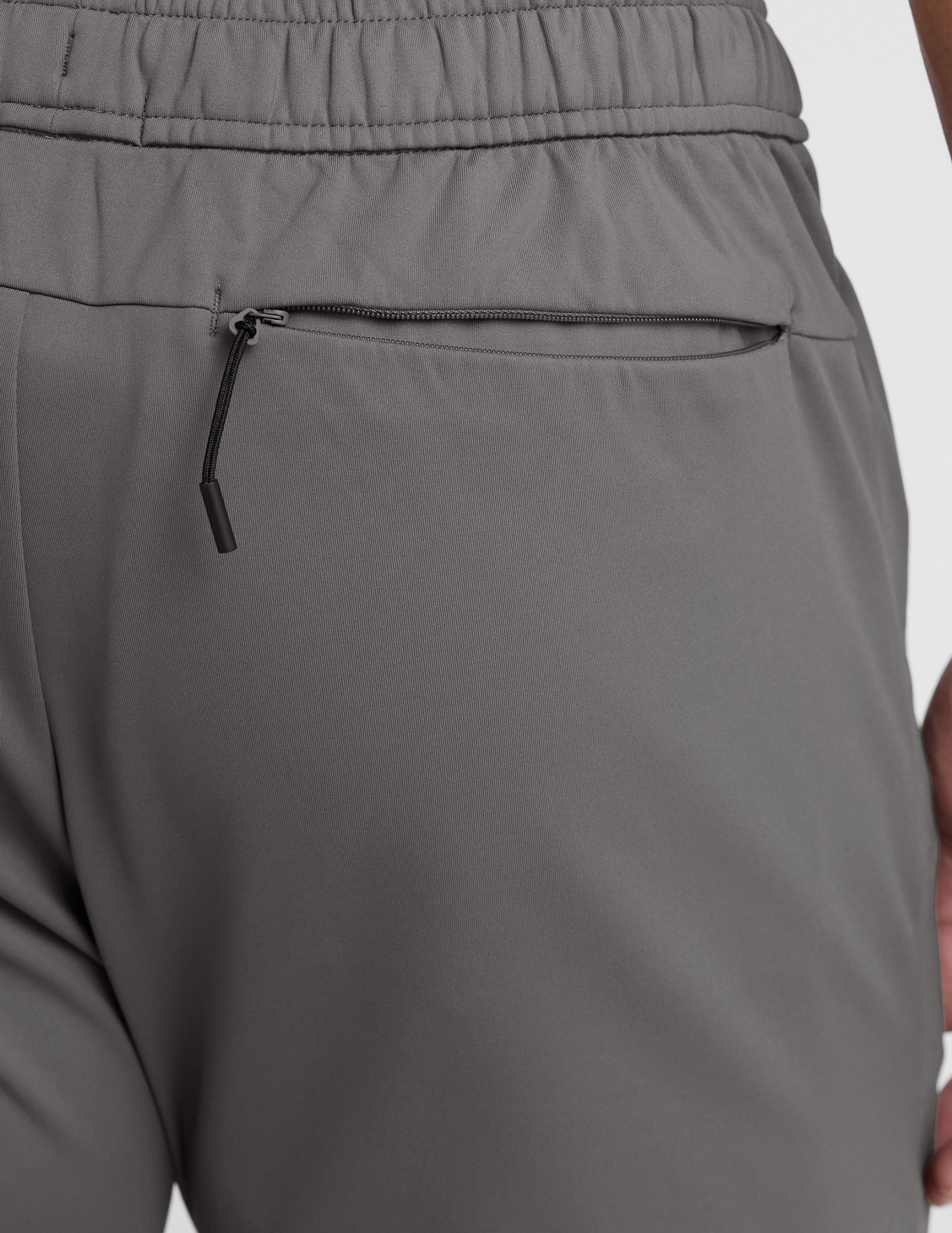 man wearing a gray shirt and gray pants on a white background.