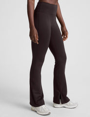 woman wearing a brown sleeveless top and pants on a white background.