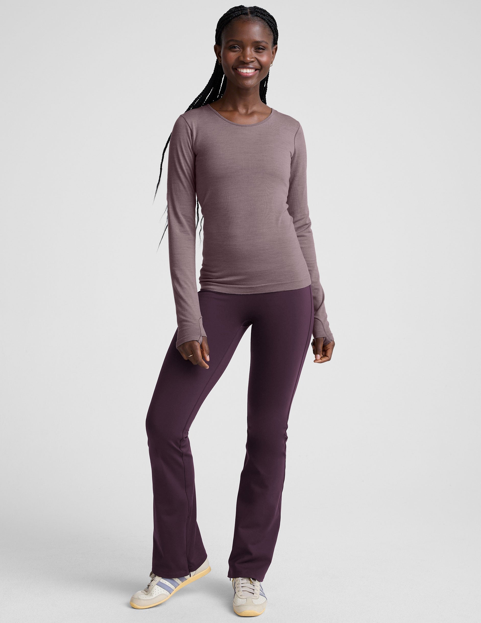woman wearing a long-sleeve top and purple pants on a white background.