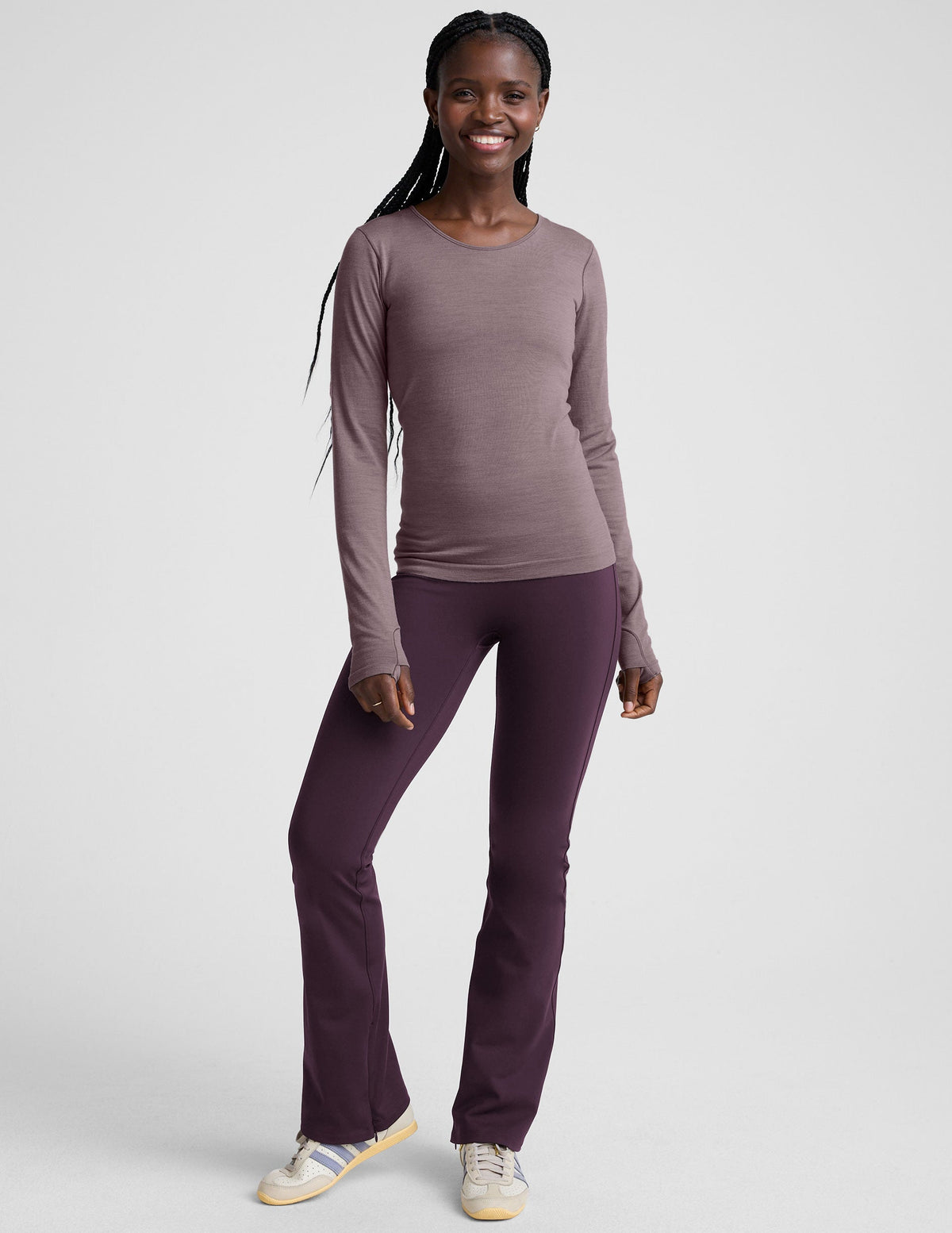woman wearing a long-sleeve top and purple pants on a white background.