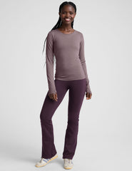 woman wearing a long-sleeve top and purple pants on a white background.