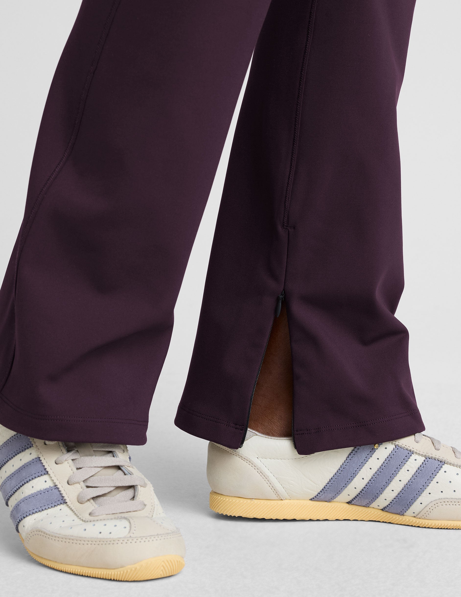 person wearing dark purple pants on a light gray background.