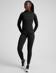 woman wearing a black jacket and high-waisted long length leggings with pockets athletic outfit on a plain background.