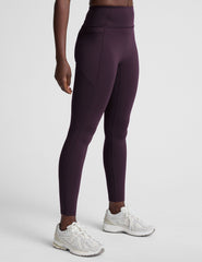 woman wearing high-waisted purple long length leggings with pockets against a plain background.