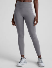 woman wearing gray high-waisted long length leggings on a plain background.