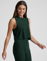 model wearing a green sleeveless cropped top and green leggings on a light gray background.