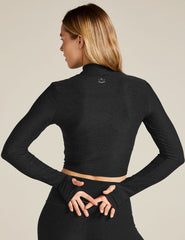 Woman wearing a black long-sleeve top and leggings on a beige background
