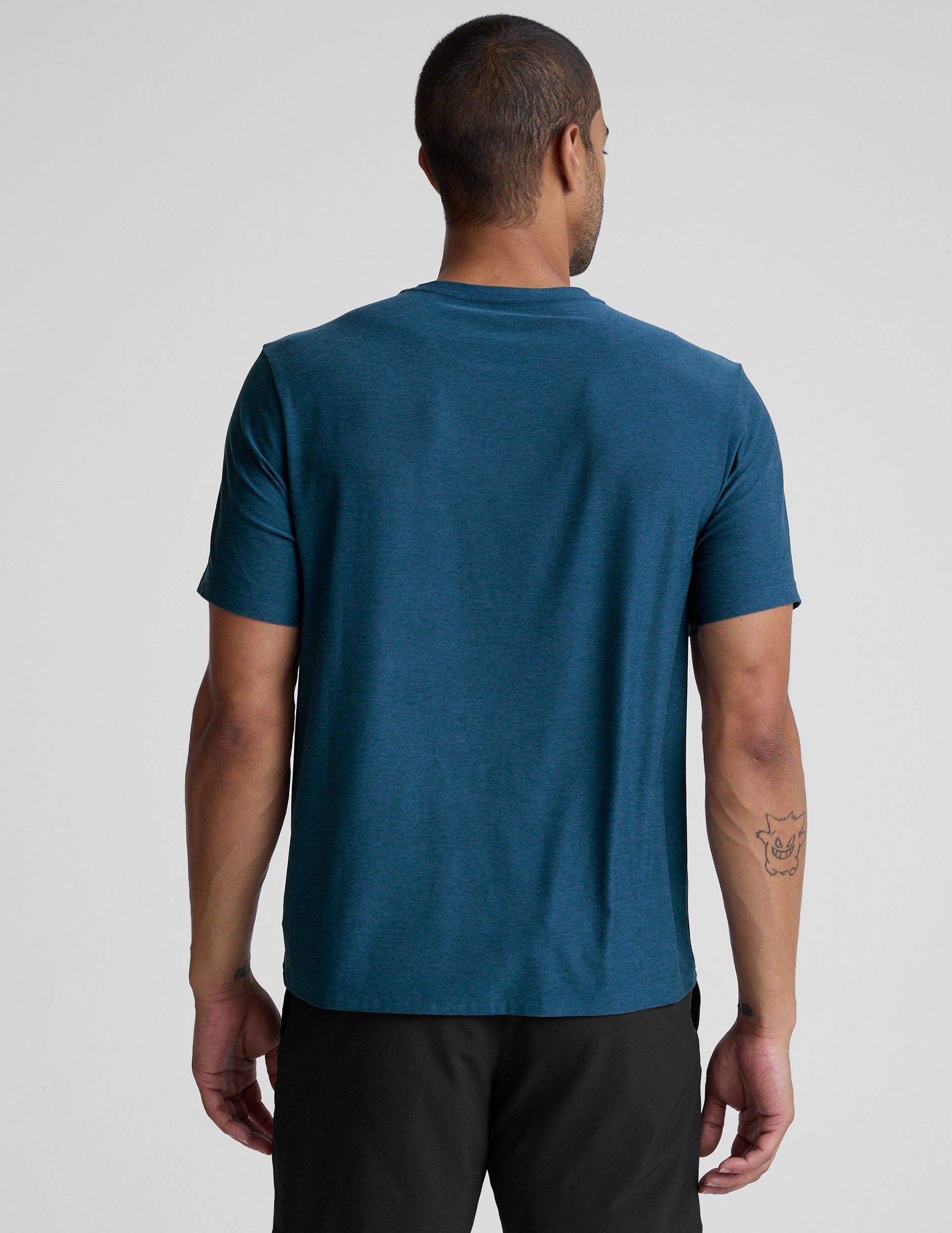man wearing a blue t-shirt and black shorts against a plain background.