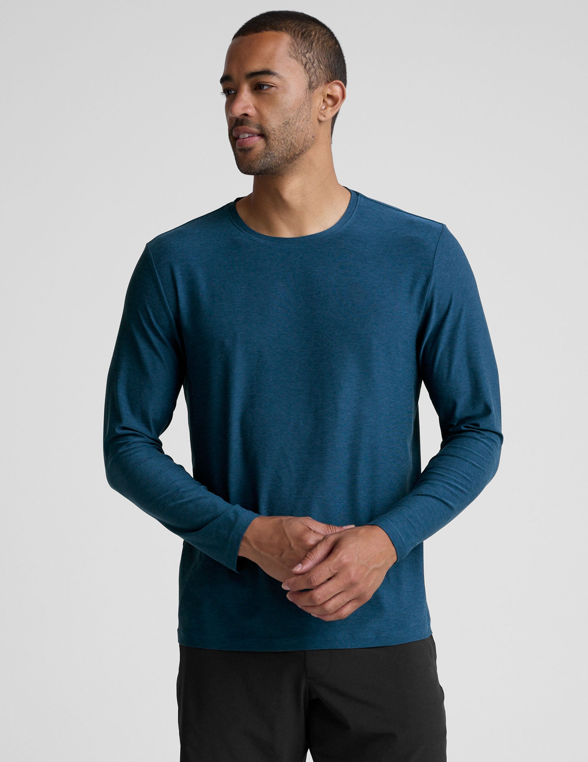 man wearing a blue long-sleeve shirt and black shorts against a gray background.