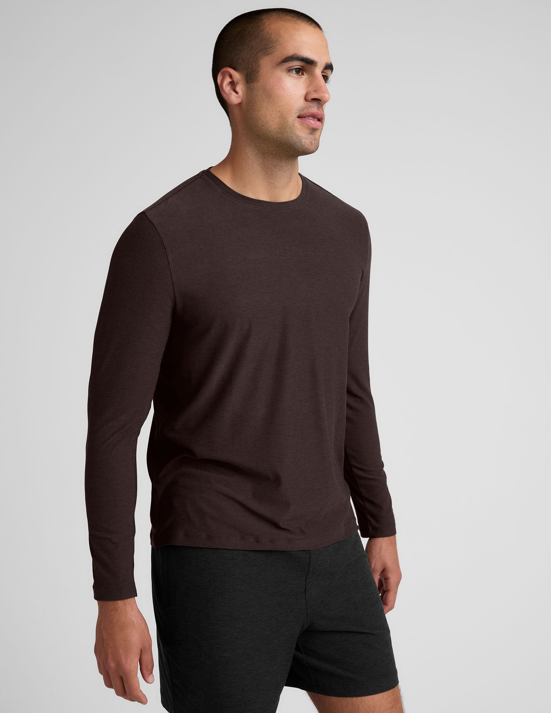 model wearing a brown men's long-sleeve shirt against a gray background.