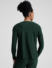 model wearing a green maternity crew neck long-sleeve top and leggings against a light gray background.