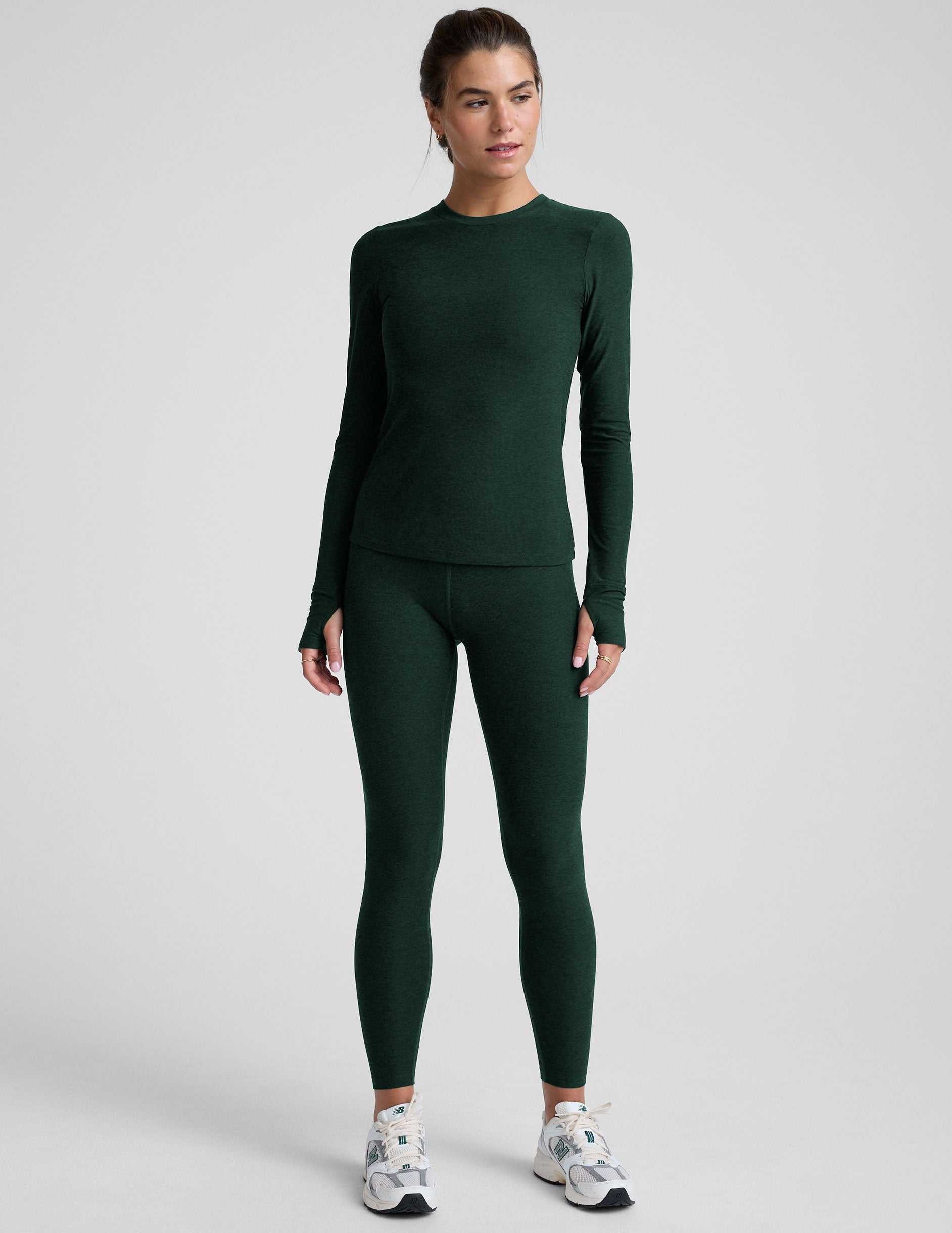model wearing a green fitted crew neck long-sleeve top against a light gray background.