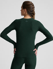 model wearing a green fitted crew neck long-sleeve top against a light gray background.