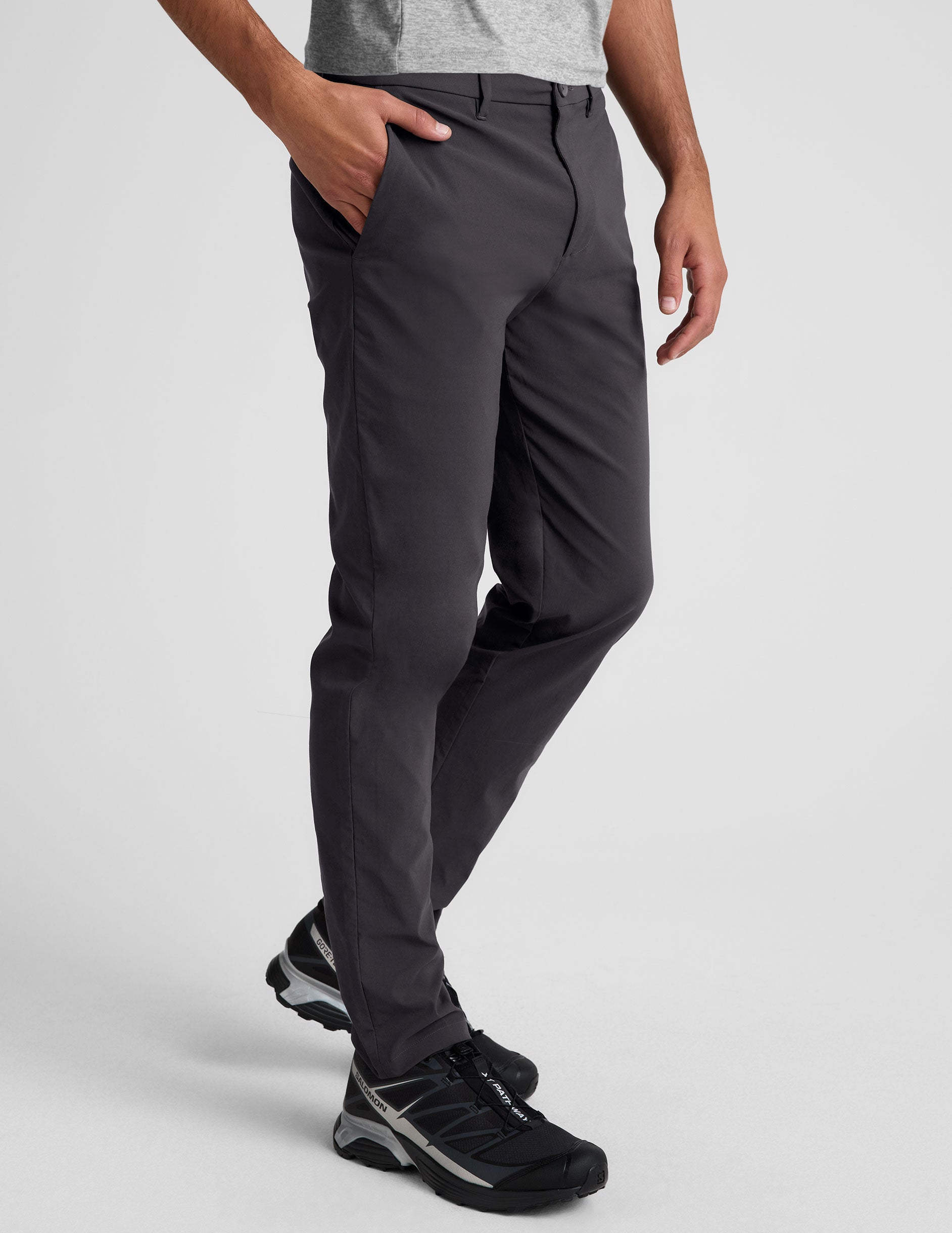 male model wearing a grey t-shirt and chino pants on a light background.