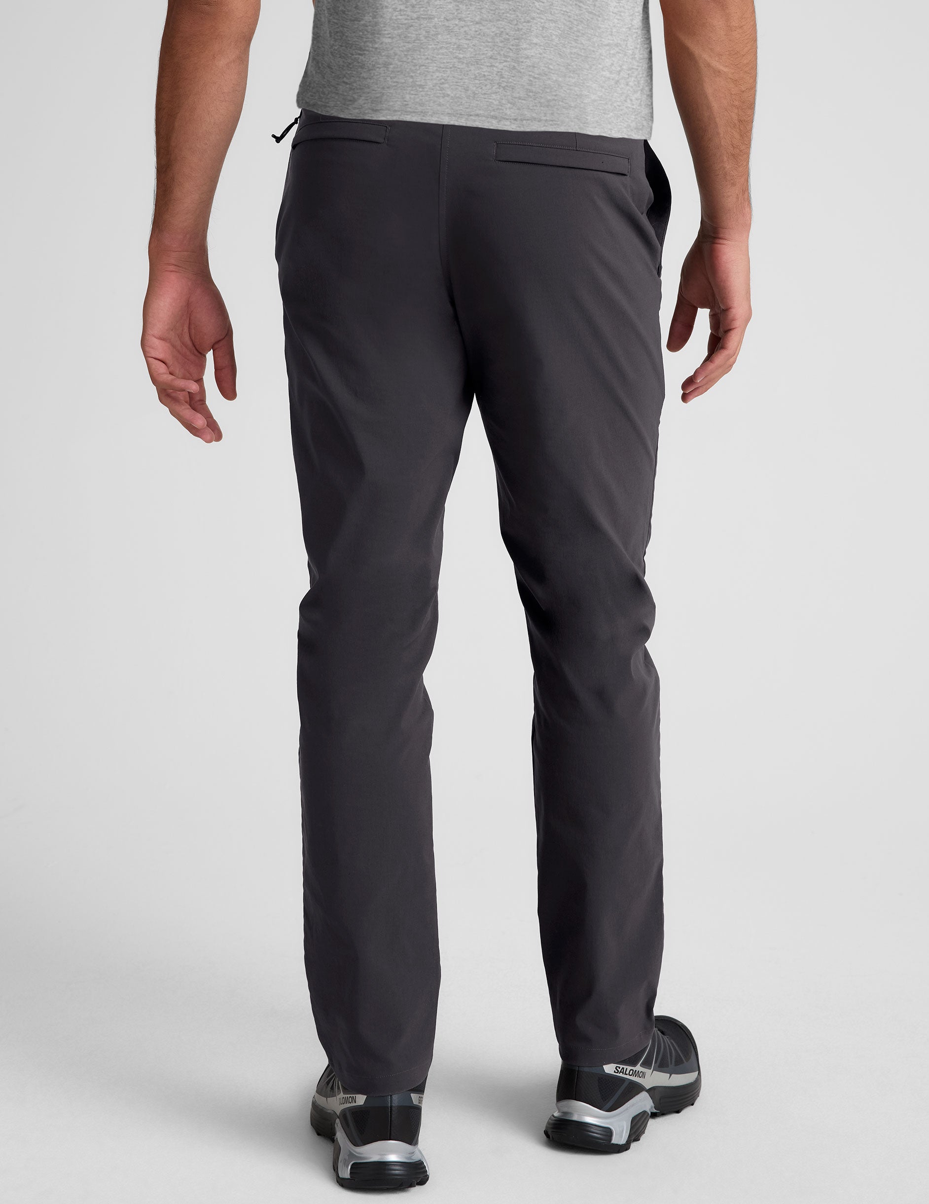 male model wearing a grey t-shirt and chino pants on a light background.