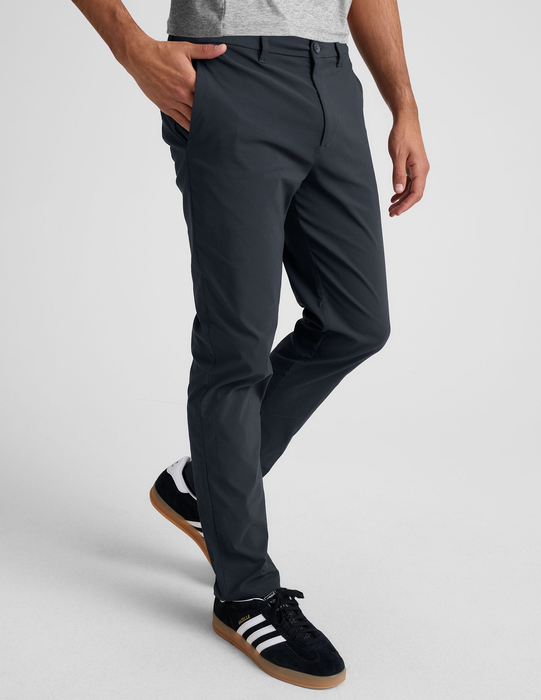 man wearing a gray t-shirt and navy chino pants with pockets against a plain background.