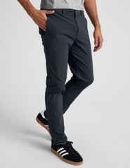 man wearing a gray t-shirt and navy chino pants with pockets against a plain background.