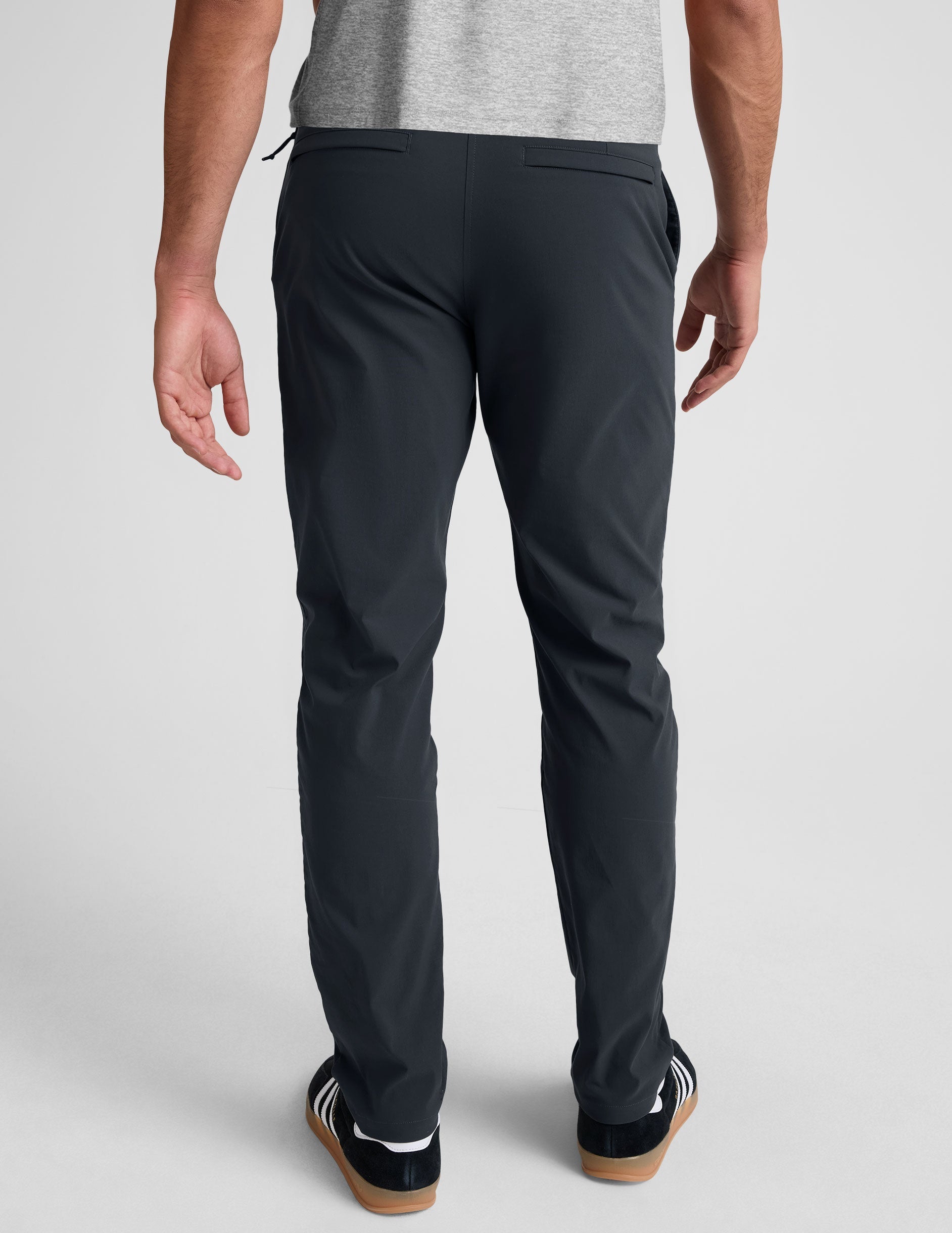 man wearing a gray t-shirt and navy chino pants with pockets against a plain background.