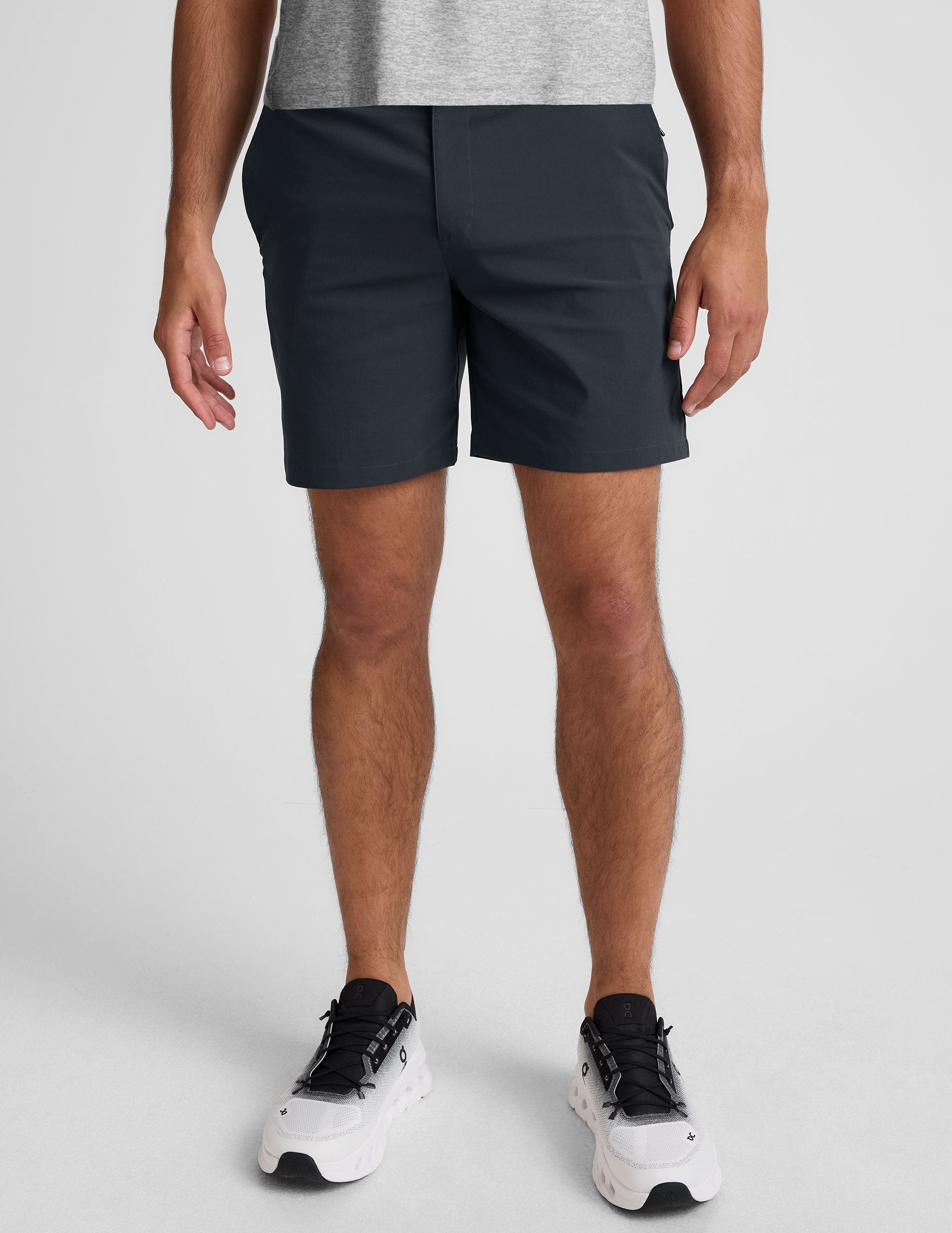 man wearing a gray crew neck t-shirt and blue chino shorts with pockets on a plain background.