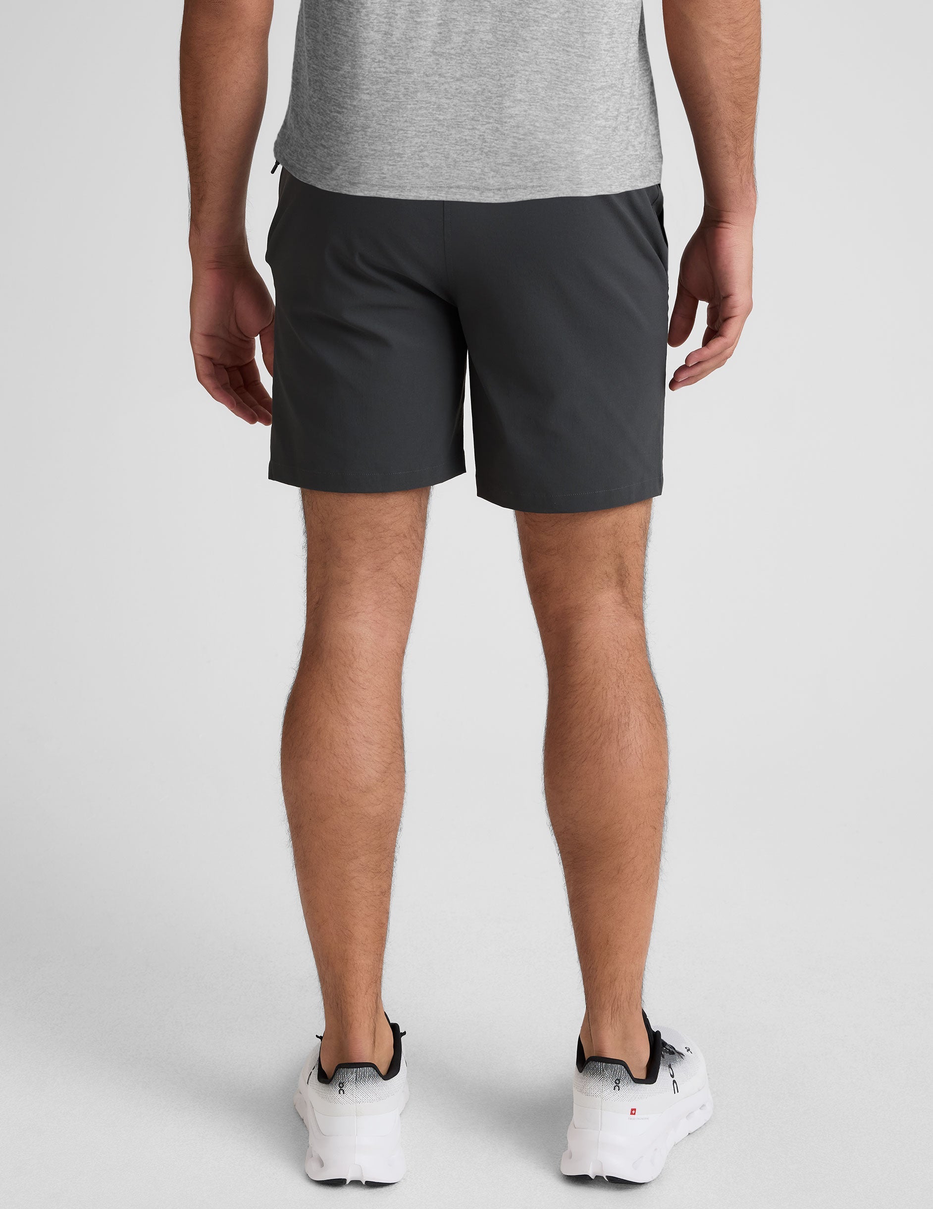 man wearing a gray crew neck t-shirt and blue chino shorts with pockets on a plain background.