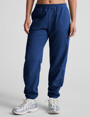 model wearing a blue cropped racerback tank and fleece joggers with pockets on a light gray background.