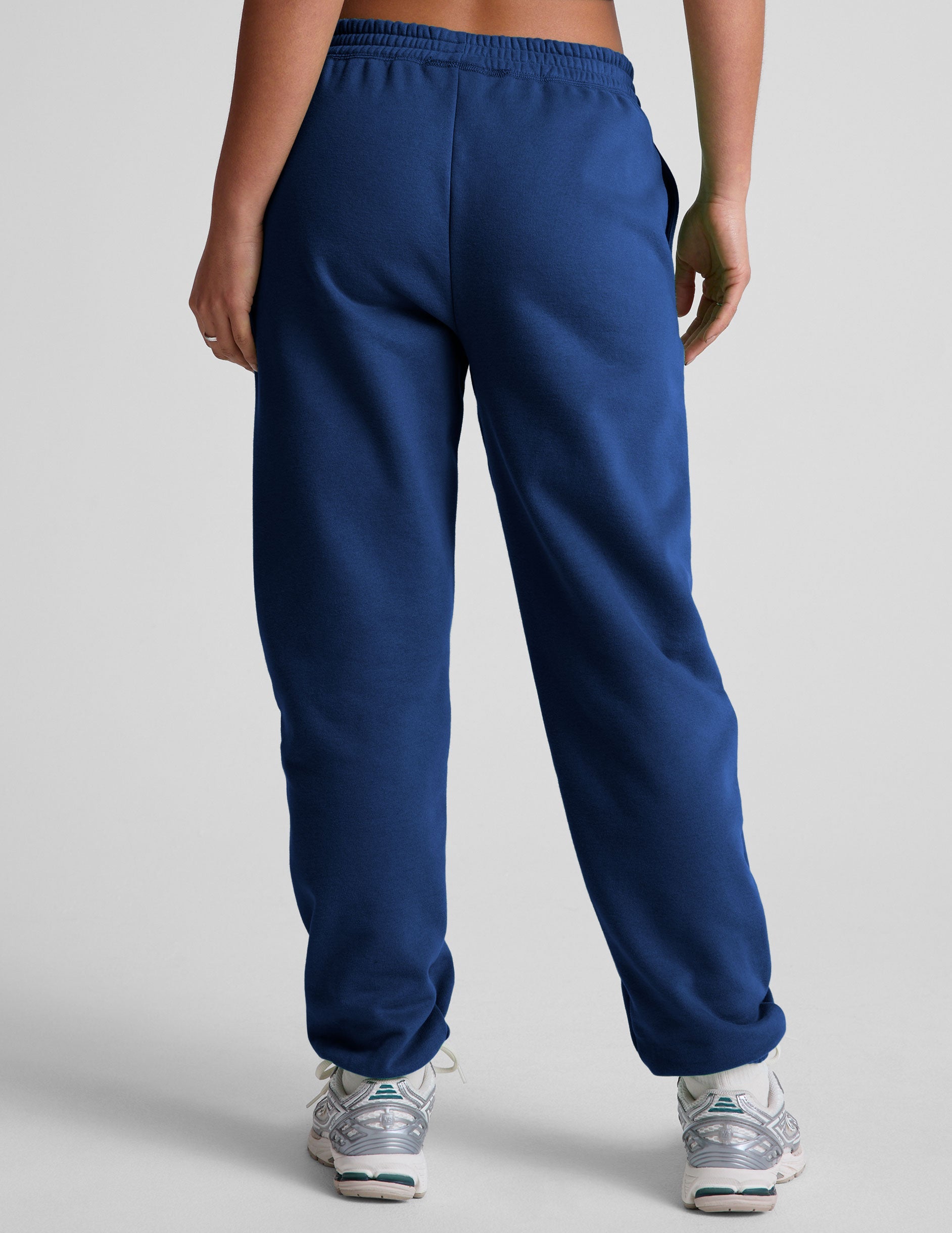 model wearing a blue cropped racerback tank and fleece joggers with pockets on a light gray background.