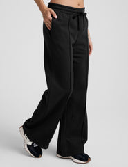model wearing a gray tank top and black wide-leg pants on a plain background.
