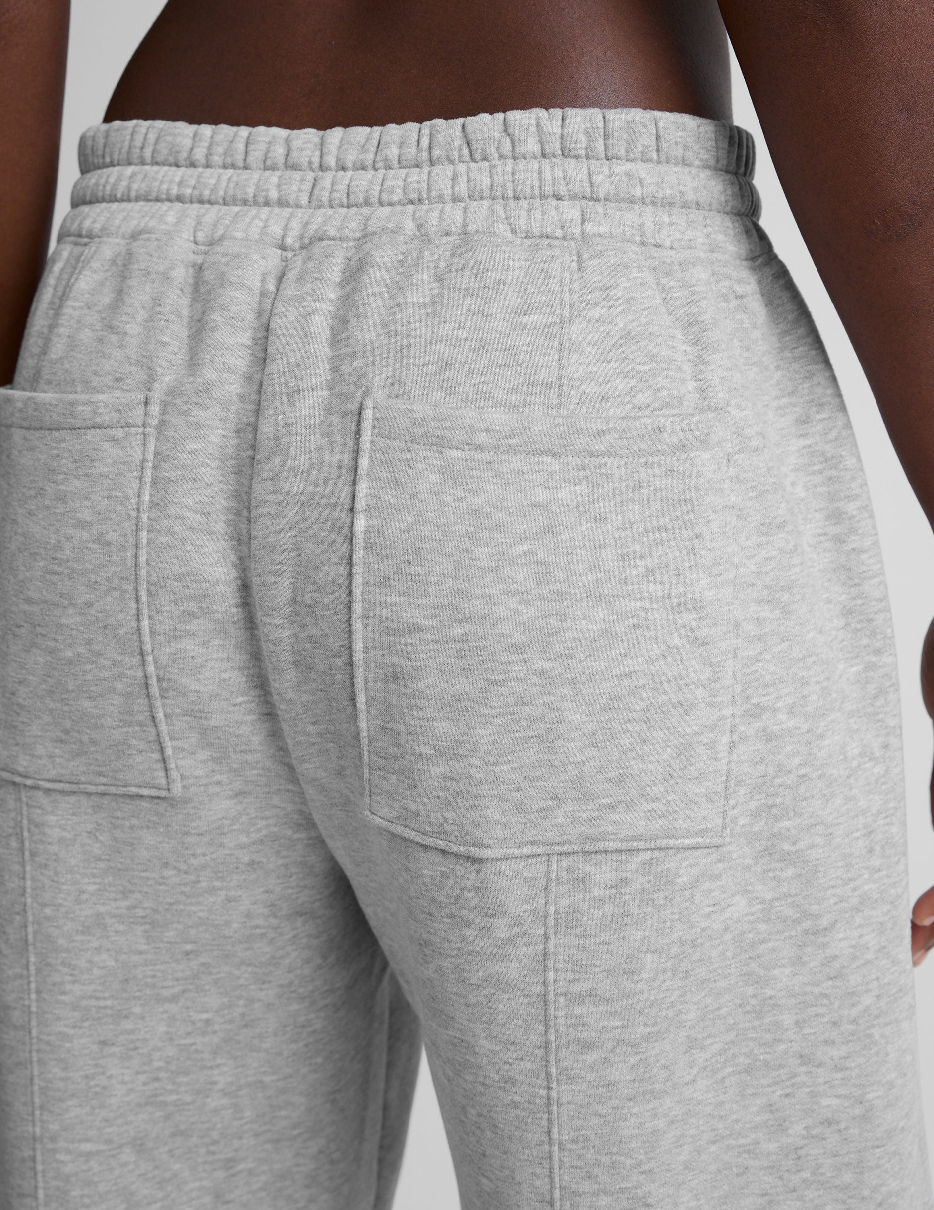 model is wearing gray fleece barrel style sweatpants against a plain background.