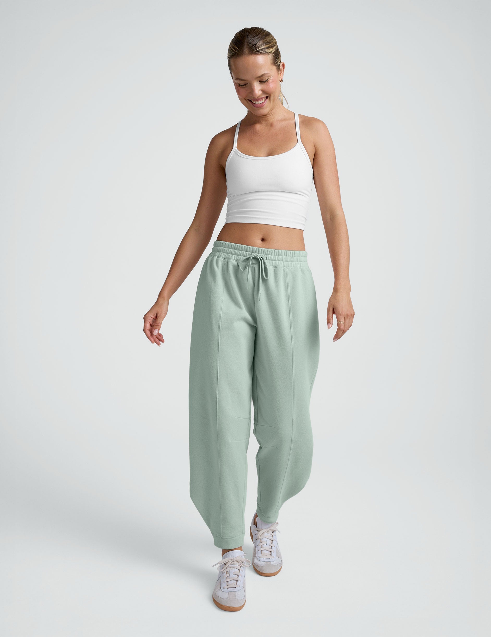 model wearing a white cropped tank and blue barrel style sweatpants against a plain background.