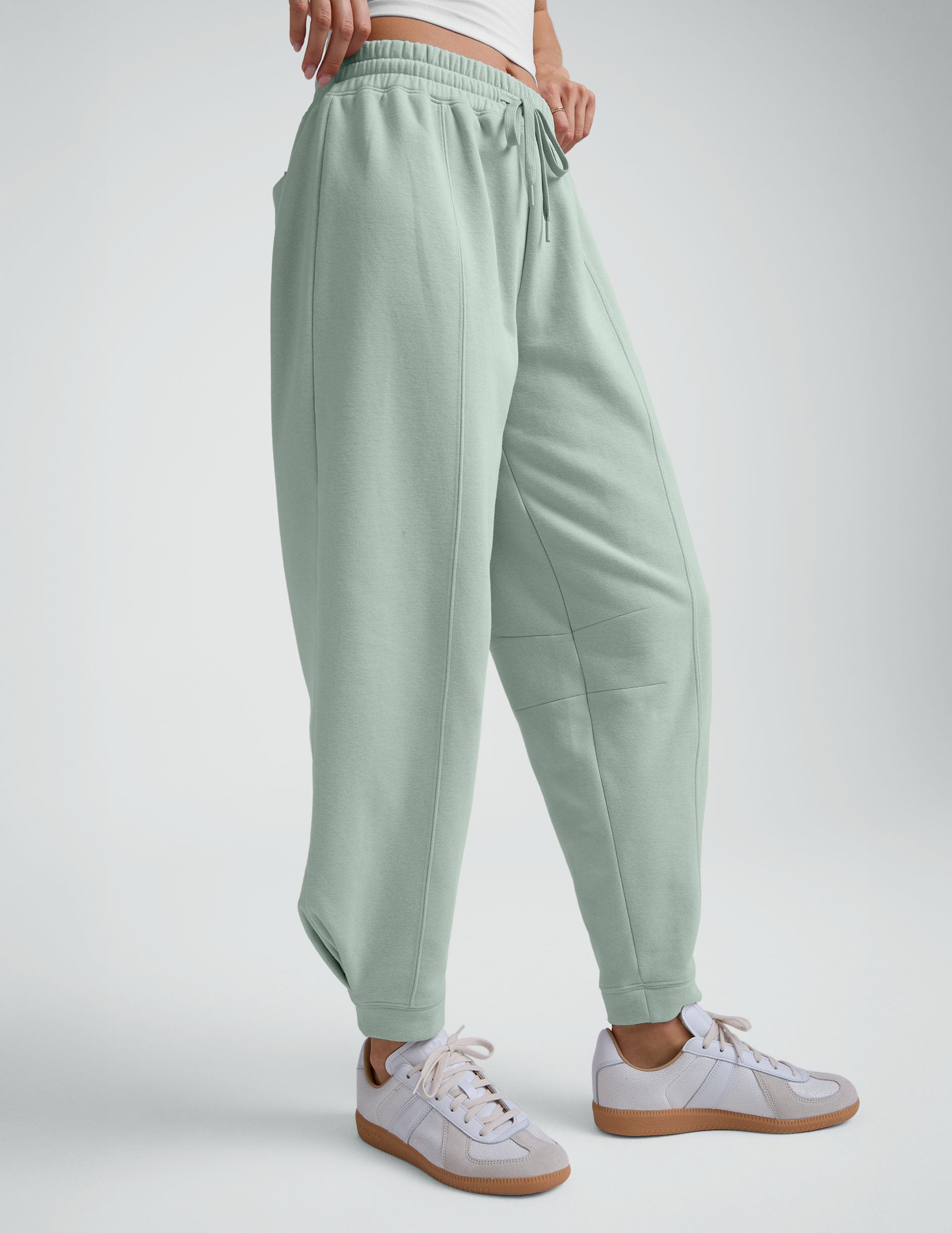model wearing a white cropped tank and blue barrel style sweatpants against a plain background.