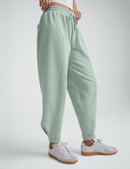 model wearing a white cropped tank and blue barrel style sweatpants against a plain background.