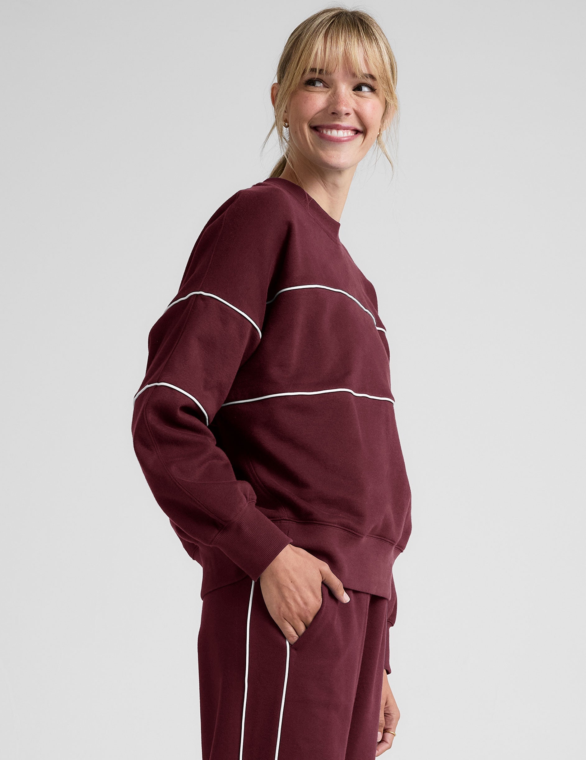 red fleece crewneck sweater with white contrast piping trim at chest and sleeves.