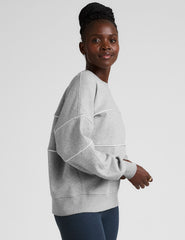 gray fleece crewneck sweater with white contrast piping trim at chest and sleeves.