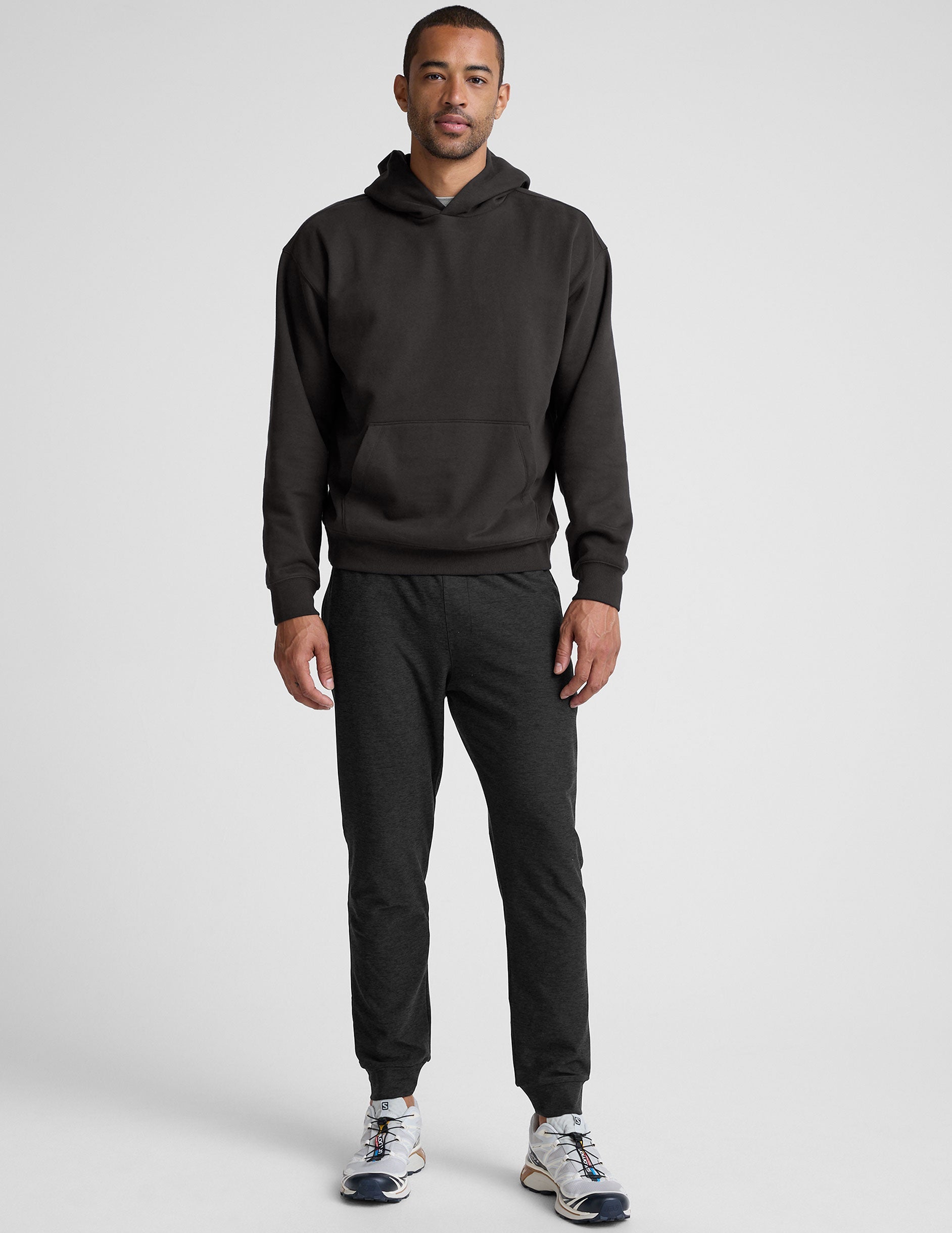 man wearing a black hoodie on a plain background.