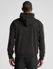 man wearing a black hoodie on a plain background.