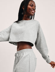 woman wearing a gray cropped sweatshirt and matching barrel fleece pants on a plain background.
