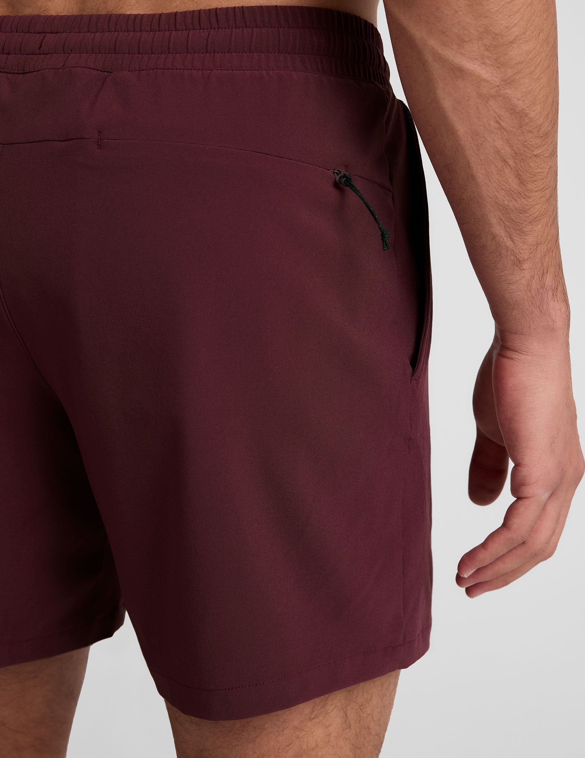 man wearing a grey t-shirt and maroon lined shorts set on a white background.