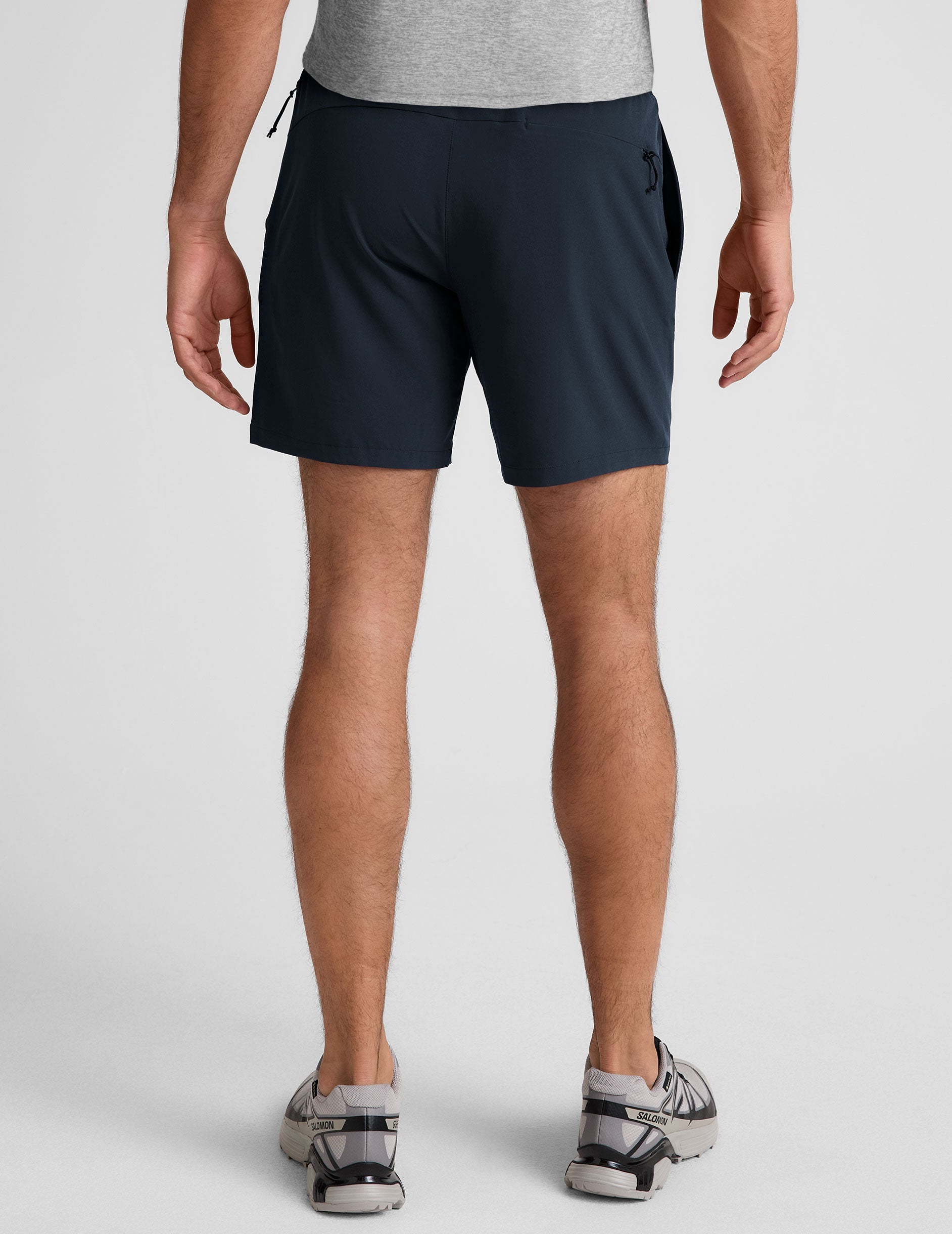 man wearing a grey t-shirt and navy blue lined shorts set on a plain background.