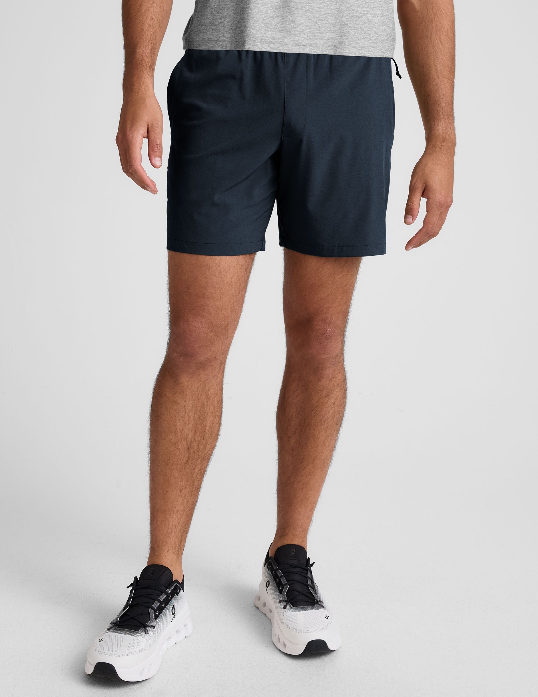 man wearing a navy t-shirt and blue shorts on a white background.